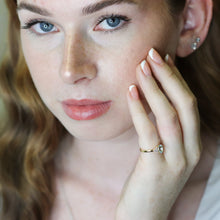 Close-up of a person wearing an aquamarine ring with diamond accents.