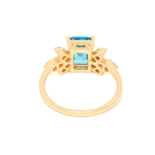 Gold ring with a blue gemstone on a white background