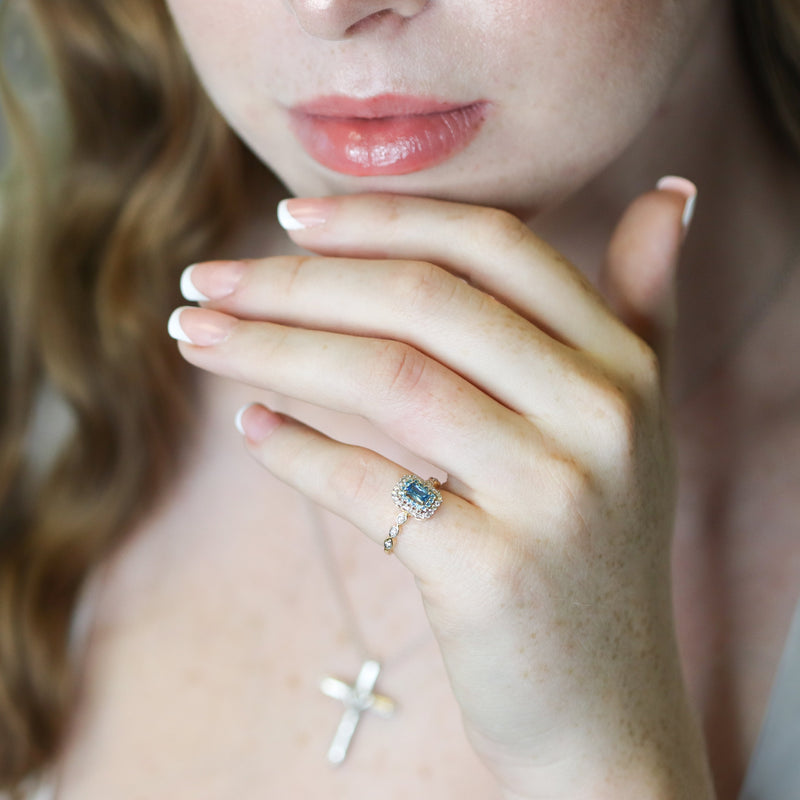 Close-up of a hand with a topaz ring in gold and diamonds.