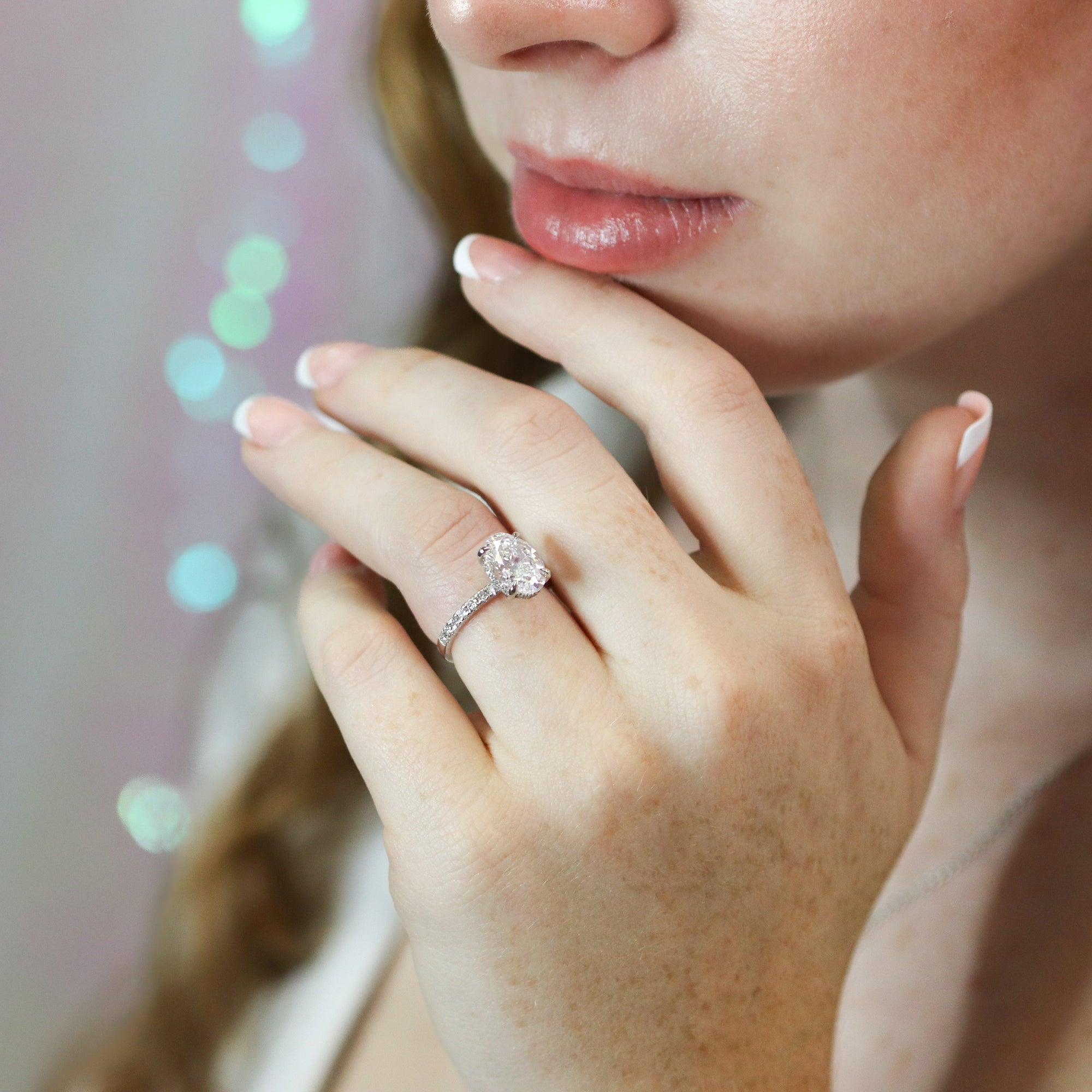 Close-up of a woman's hand with a ring, blurred lights in the background