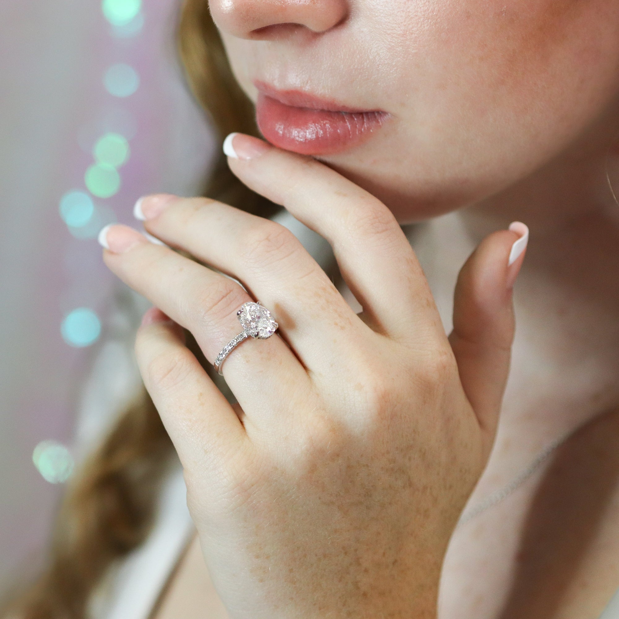 Close-up of a woman's hand with a ring, blurred lights in the background.