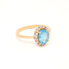 Gold ring with a blue gemstone and diamond accents on a white background