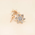 Gold star-shaped earring with clear gemstones on a beige background