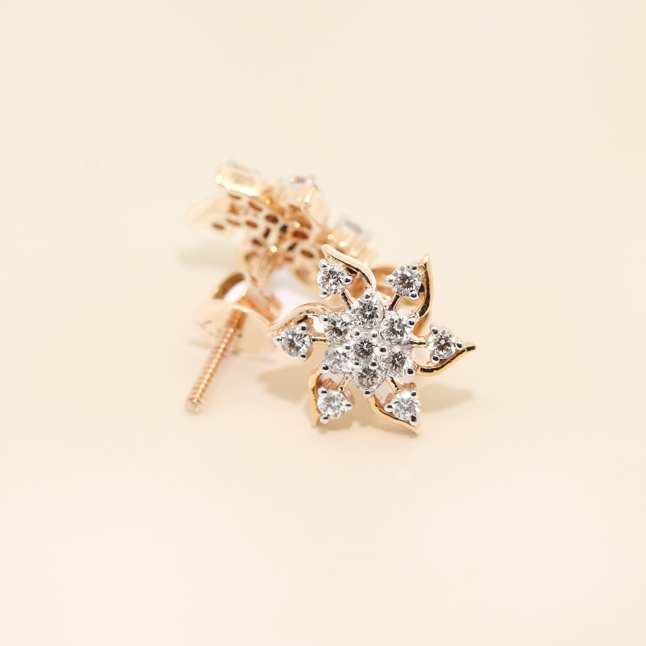 Gold star-shaped earring with clear gemstones on a beige background