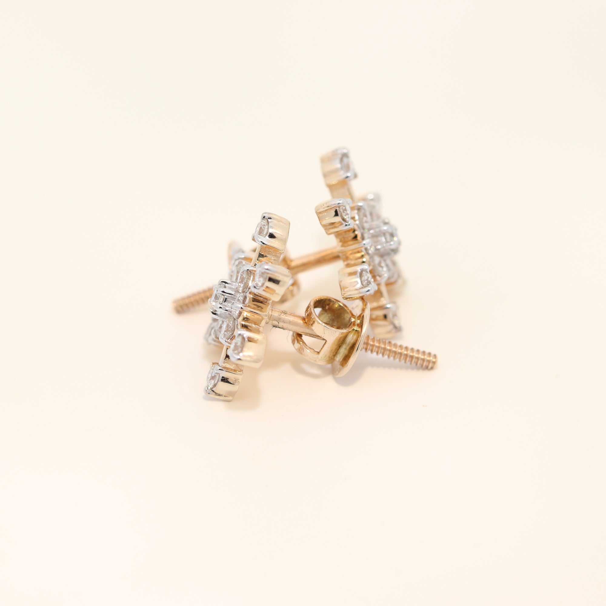 Gold and diamond earrings on a beige background