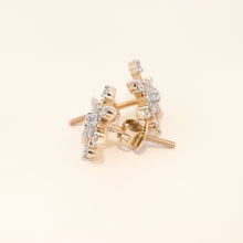 Gold and diamond earrings on a beige background