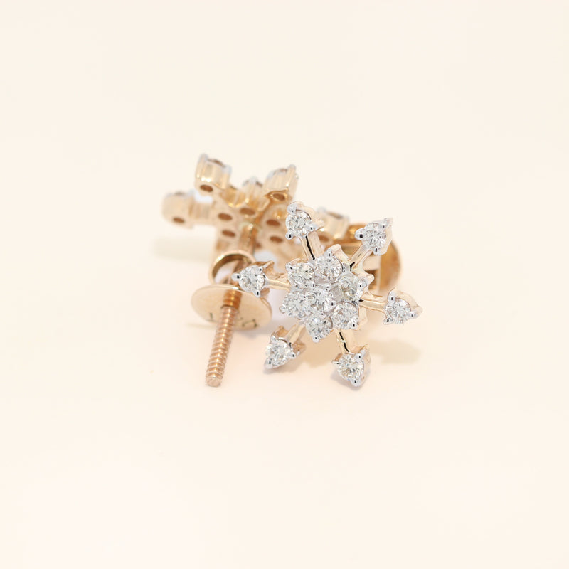Gold snowflake-shaped earrings on a light beige background