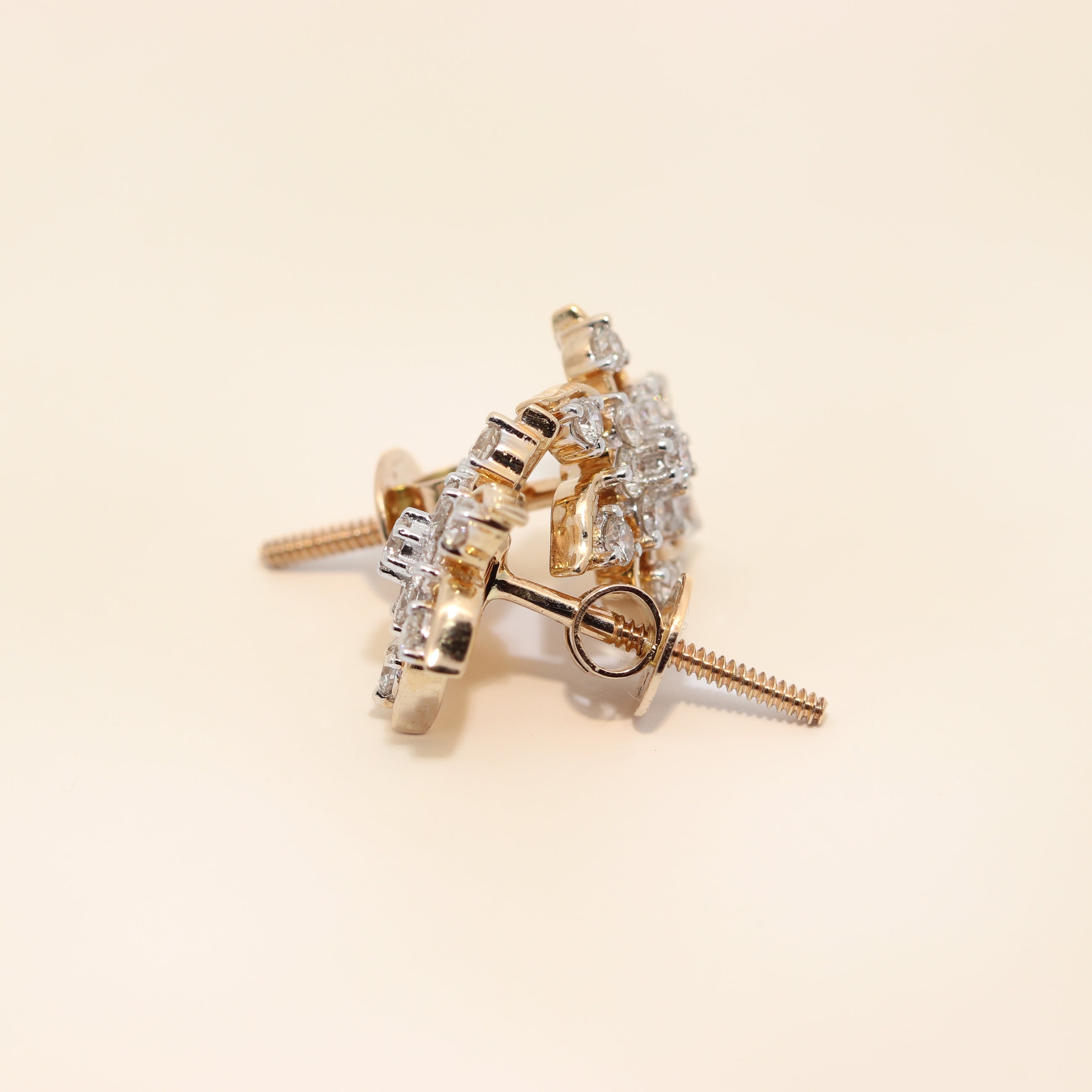 Gold earrings with diamond accents on a beige background