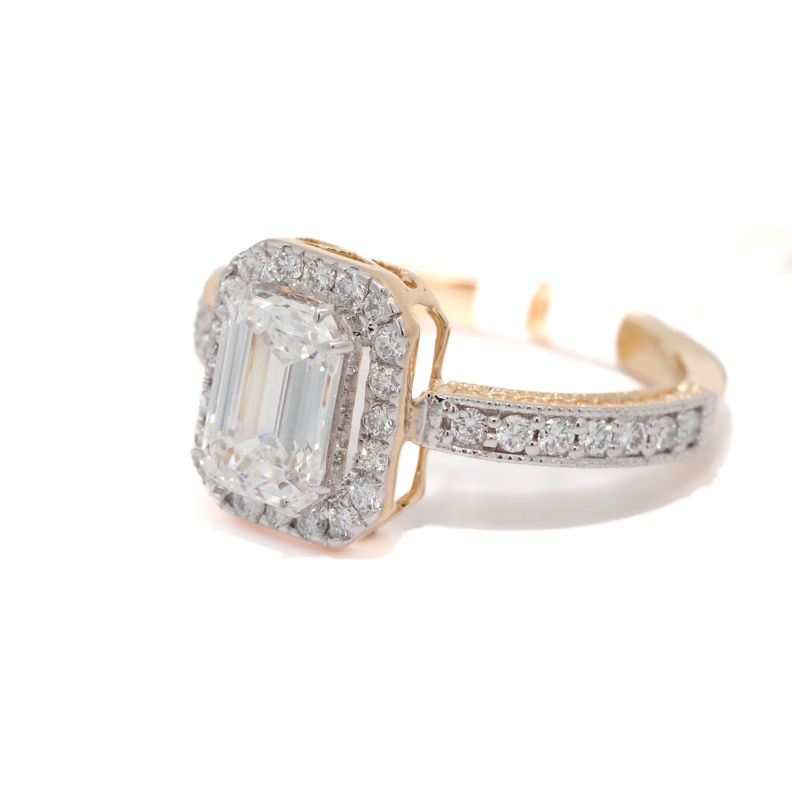Gold ring with a large emerald-cut diamond and smaller diamonds on a white background