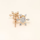 Gold and diamond earrings on a light beige background