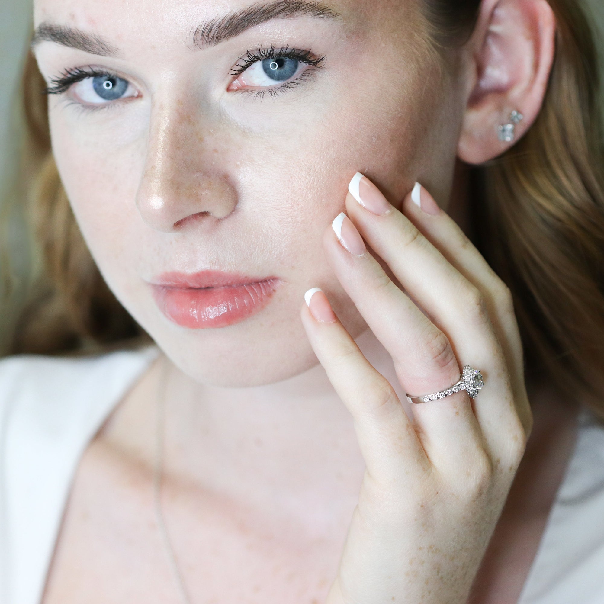 Woman wearing a diamond ring, close-up of face and hand.