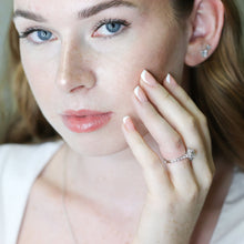 Woman wearing a diamond ring, close-up of face and hand.