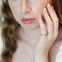 Woman wearing a gold ring with a diamond on a blurred background
