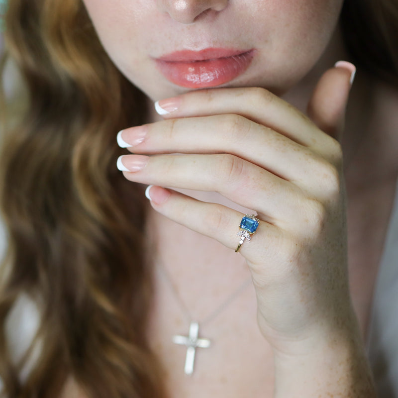 Woman wearing a ring with a blue gemstone.