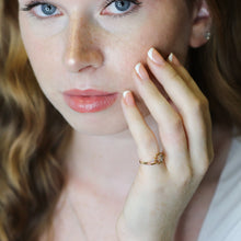 Woman with freckles and blue eyes wearing a ring, with a blurred background