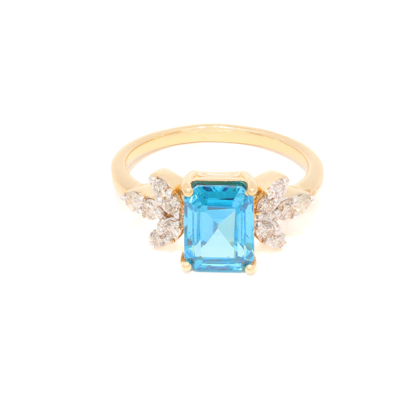 Gold ring with a blue gemstone and diamond accents on a white background