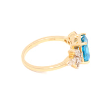 Gold ring with a blue gemstone on a white background